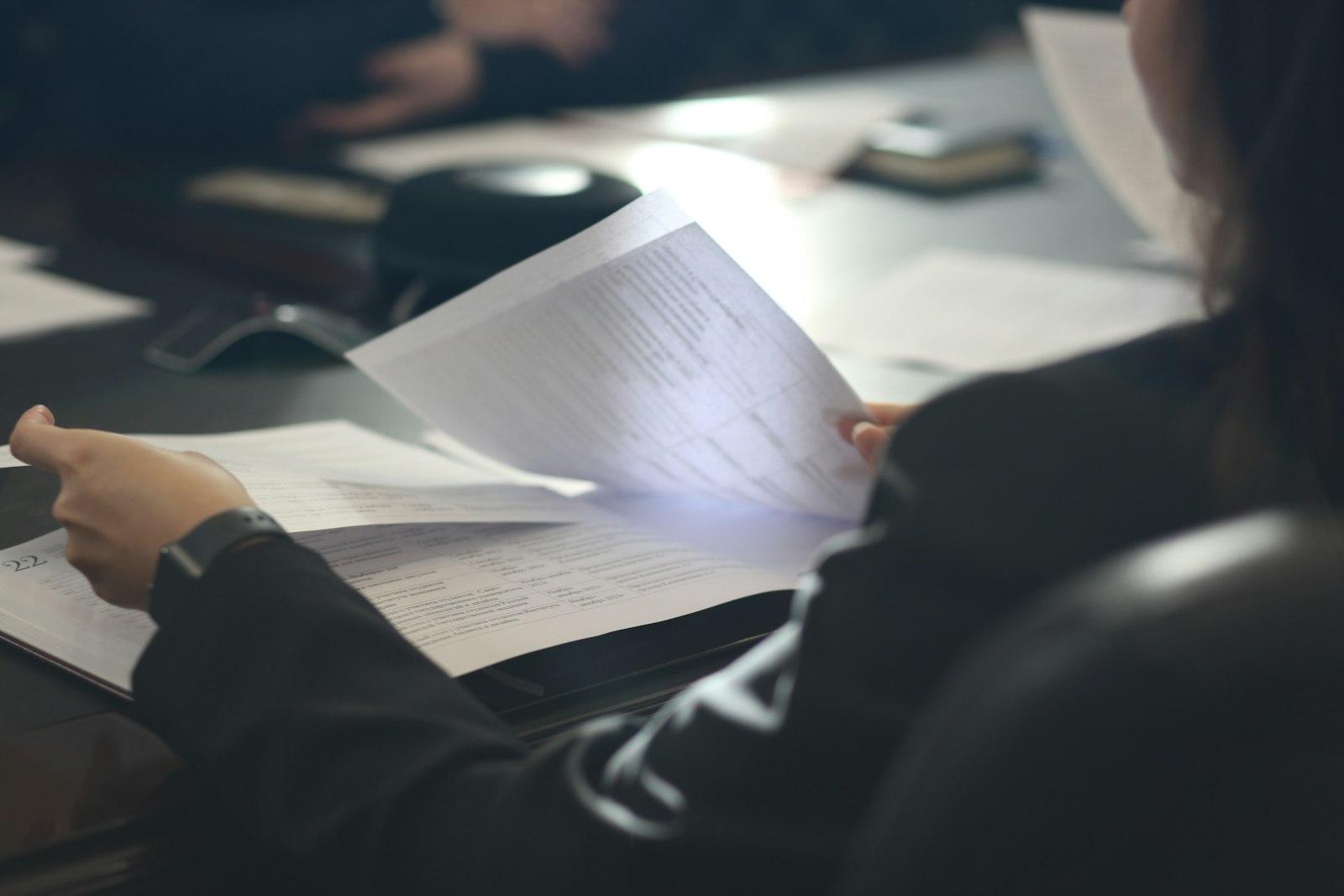 A person reading printed documents at a table