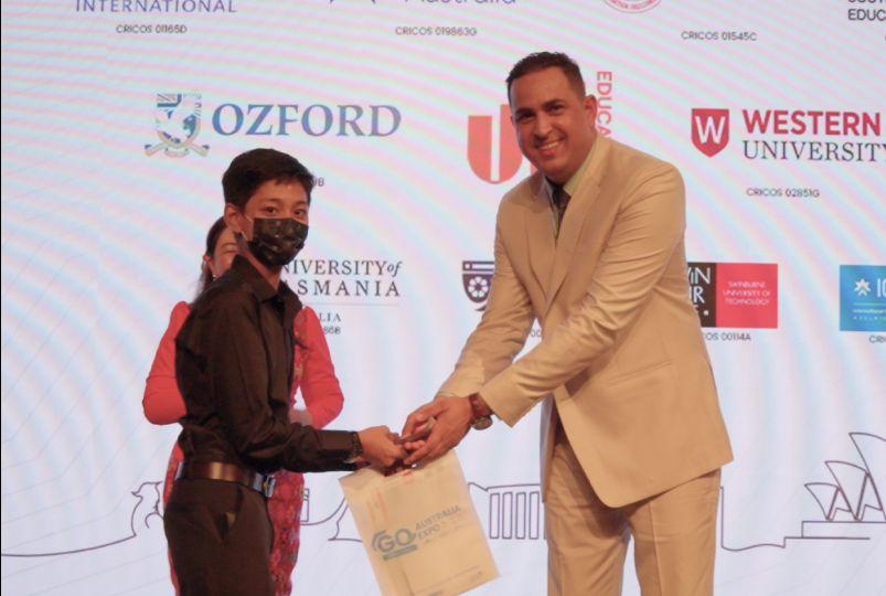 A student receiving a gift bag at an education expo