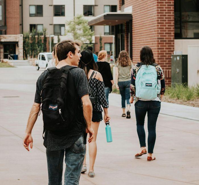 Students with backpacks walking across a campus