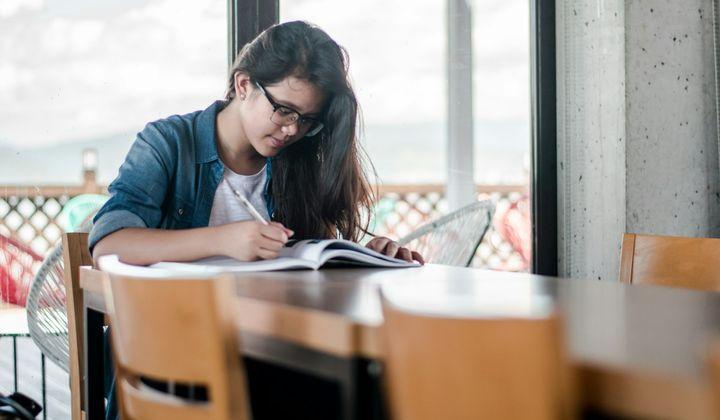A student taking notes at a desk